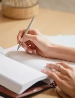 woman-s-hands-writing-in-notebook-e16901706054332